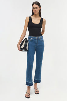 Blue straight-leg jeans with frayed hem and darker wash bands at ankles, shown with black tank top.