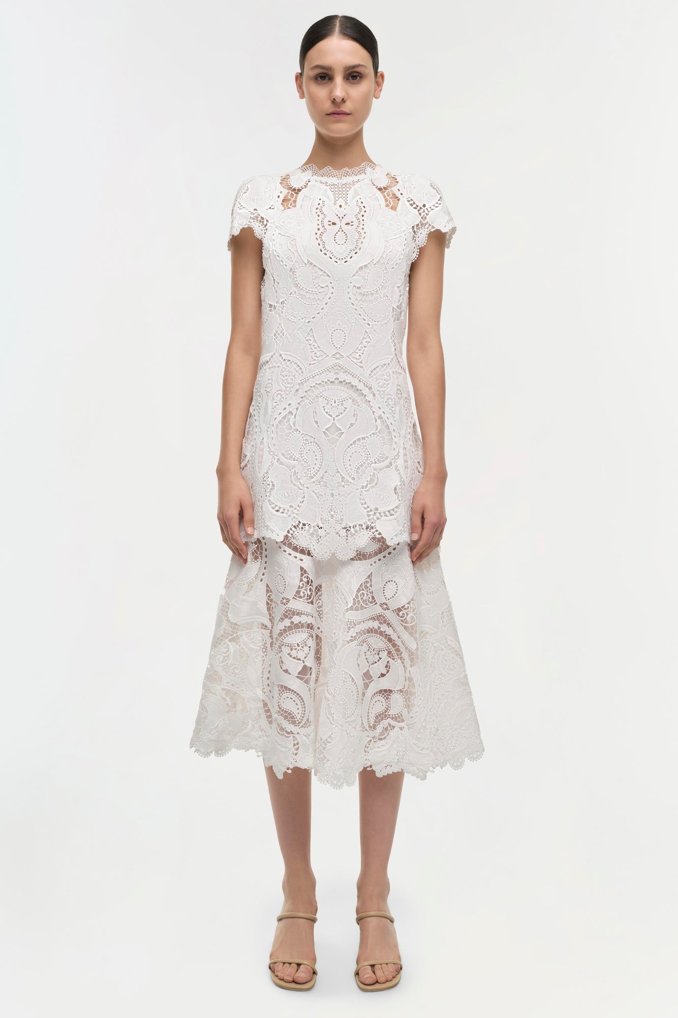 White lace midi dress with short sleeves, crew neckline, and geometric cutout patterns throughout.