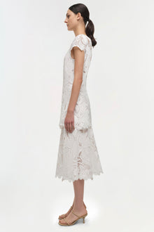 White lace midi dress with short sleeves and scalloped hem, shown on model in side view.