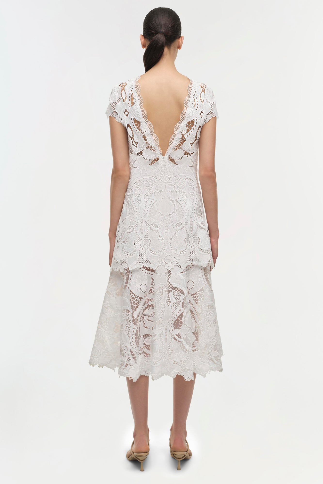 White lace midi dress with short sleeves, open back, and tiered skirt hem, shown from back view.