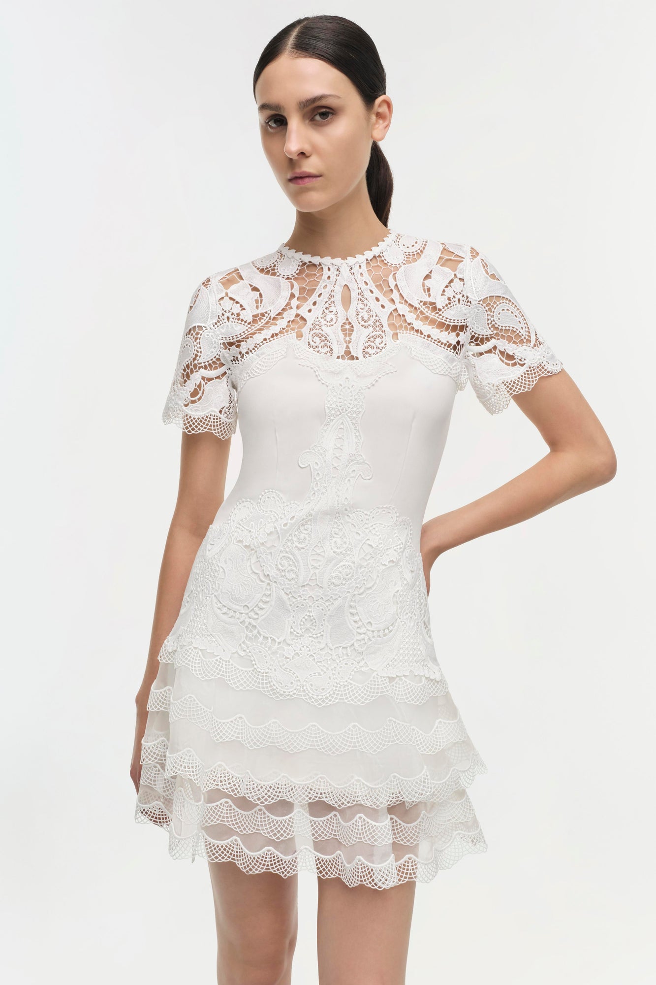 White lace dress with short sleeves, ornate paisley pattern, and tiered scalloped hem.