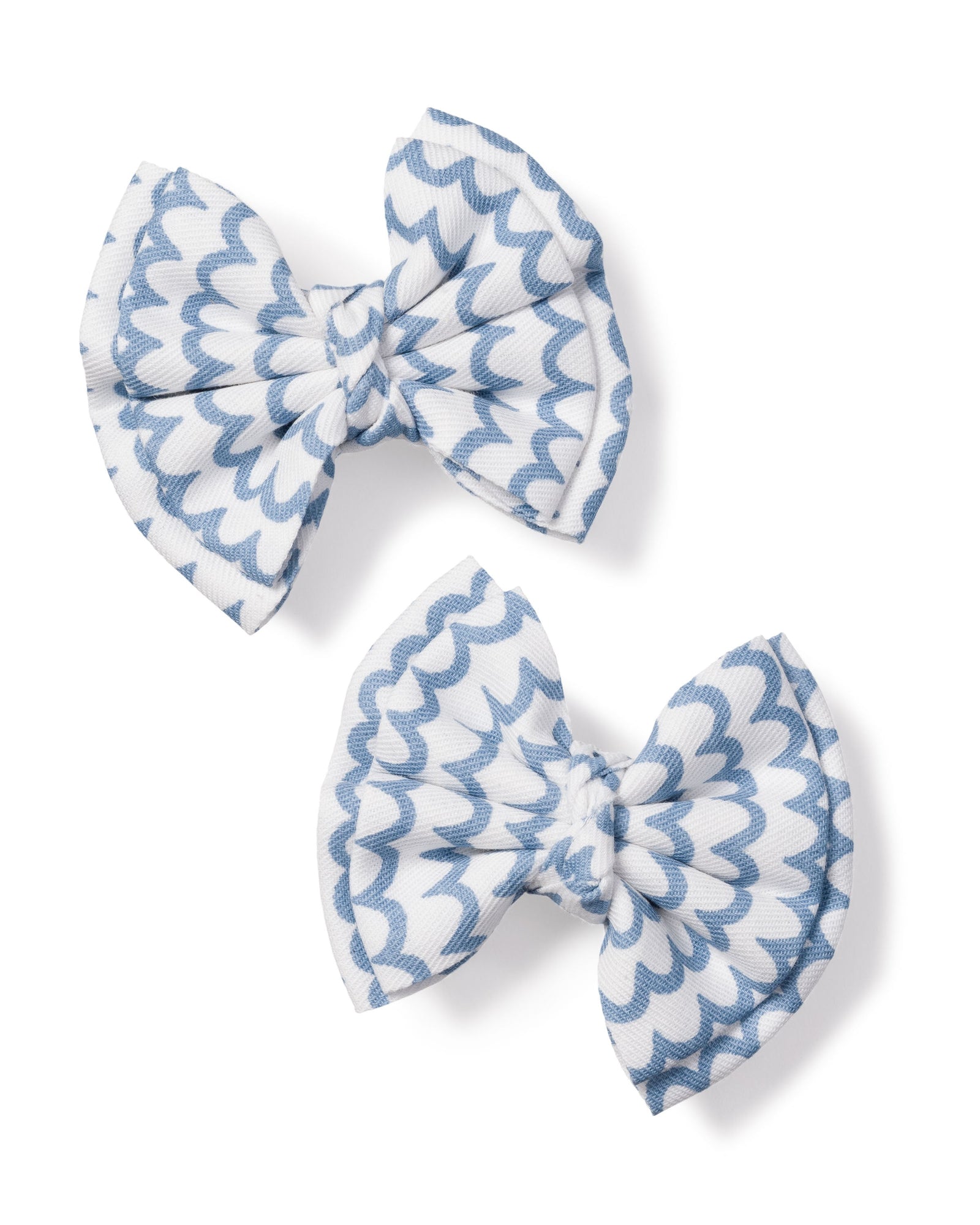 The Girls Hair Bows in La Mer by Petite Plume, featuring charming white and light blue scalloped patterns, make the perfect accessory for girls. Positioned diagonally on a plain white background, these elegant bows add a touch of sophistication to any outfit.