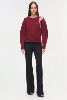 Burgundy ribbed pullover with beaded neckline and shoulder cutout, paired with black flared pants.