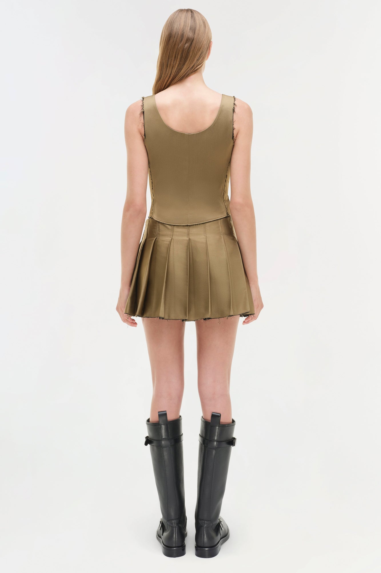 Olive green sleeveless bustier top with pleated skirt bottom, shown with black knee-high boots.
