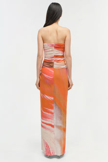 Strapless maxi gown with ruched bodice and orange, pink, and cream gradient print throughout.