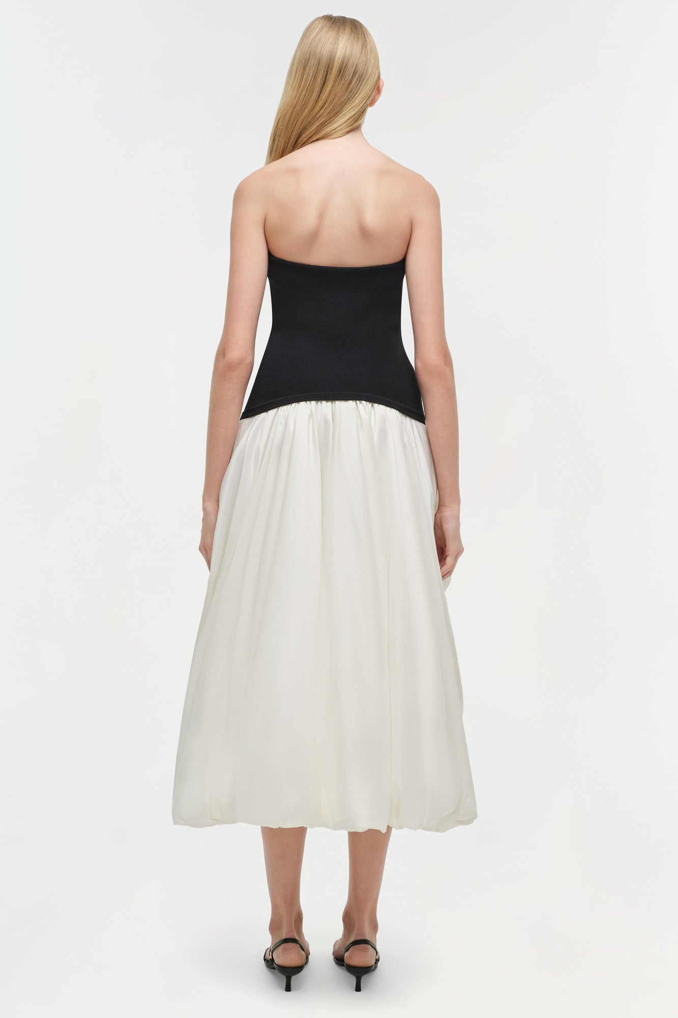 Strapless midi dress with black fitted bodice and cream gathered skirt, shown from back view.