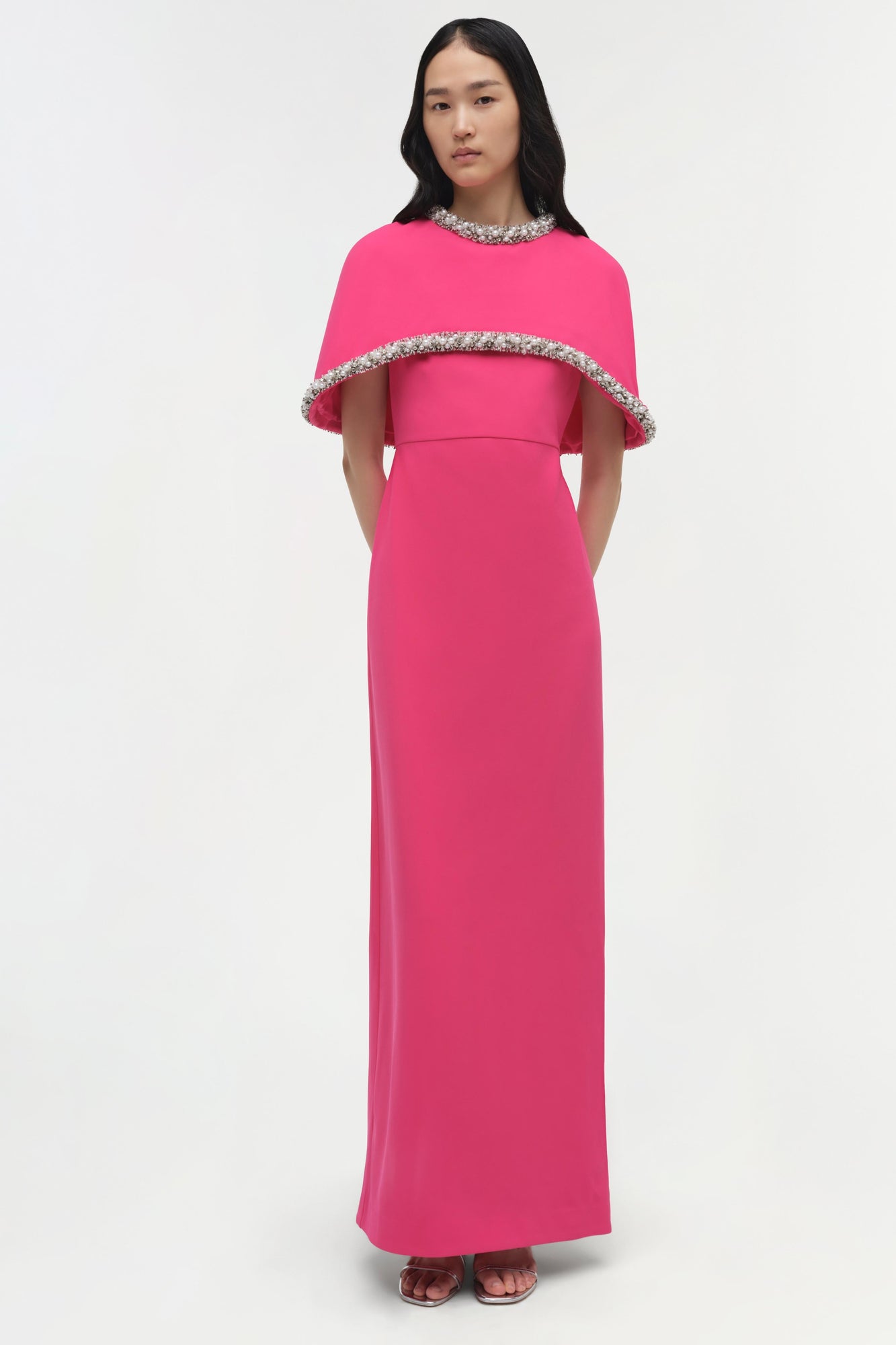 Hot pink floor-length gown with beaded cape overlay and embellished neckline.