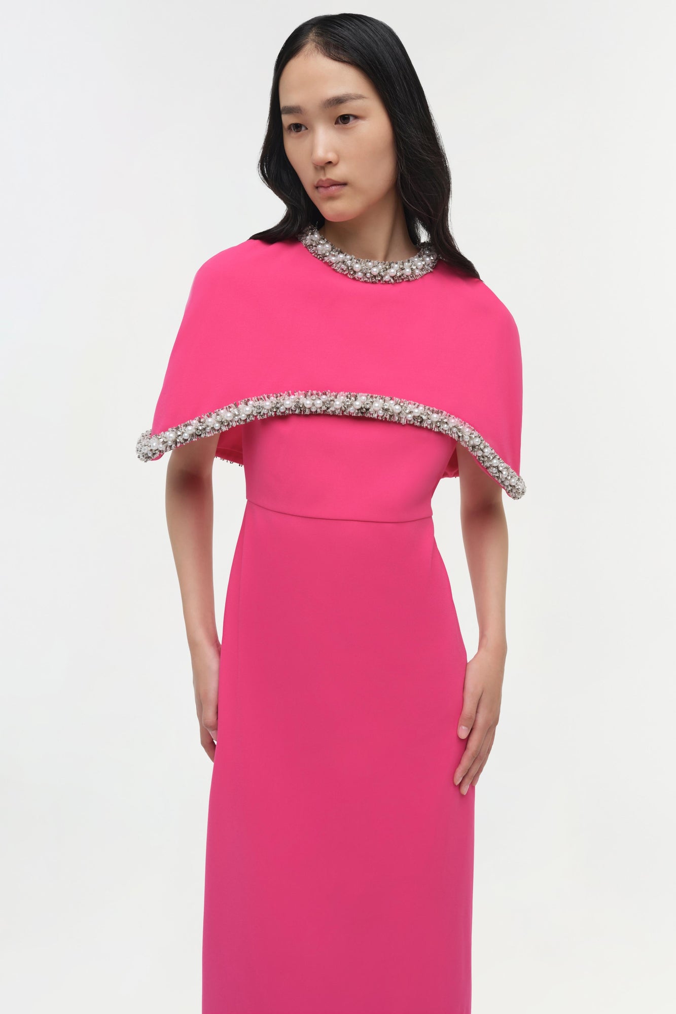 Hot pink gown with a detached cape featuring crystal embellishments at the neckline and cape edge.