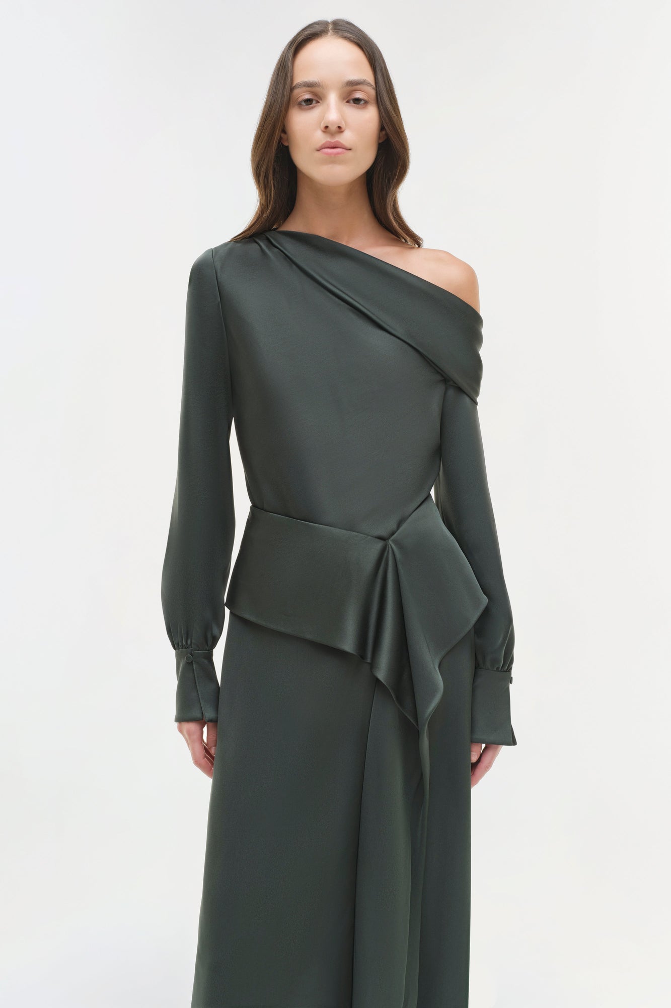 Woman wearing a charcoal satin midi skirt with asymmetrical draped top and long sleeves.