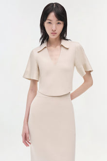 Beige linen knit midi skirt with high waist and side pockets, styled with matching short-sleeve collared top.
