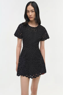 Black mini dress with allover eyelet embroidery, short puffed sleeves, and scalloped hem.