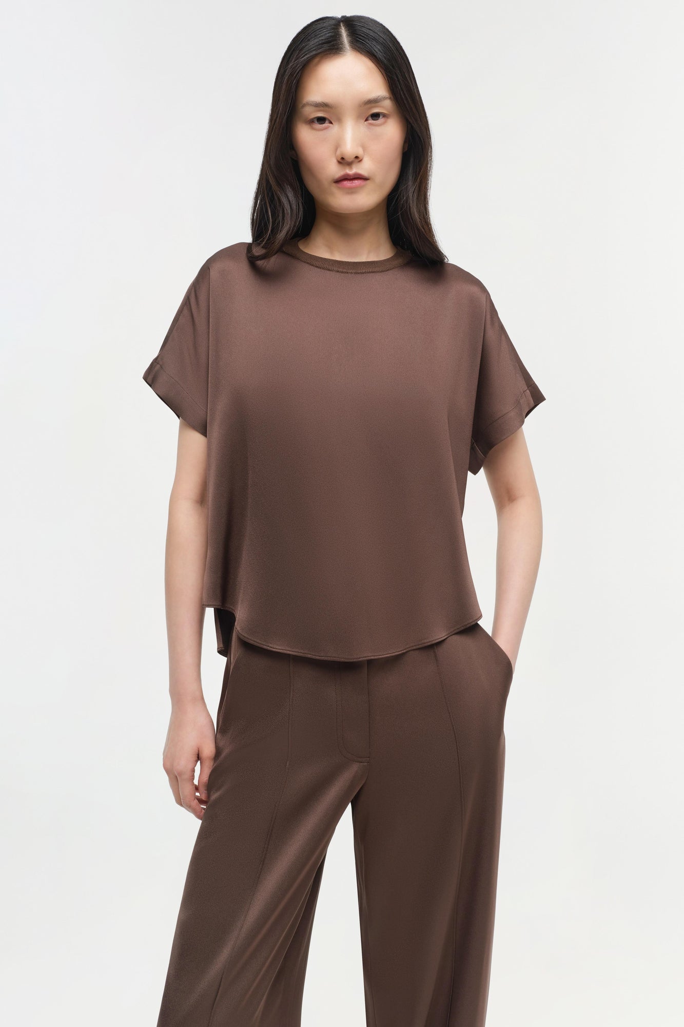 Brown satin t-shirt with short sleeves and crew neckline, displayed on a model wearing matching brown pants.