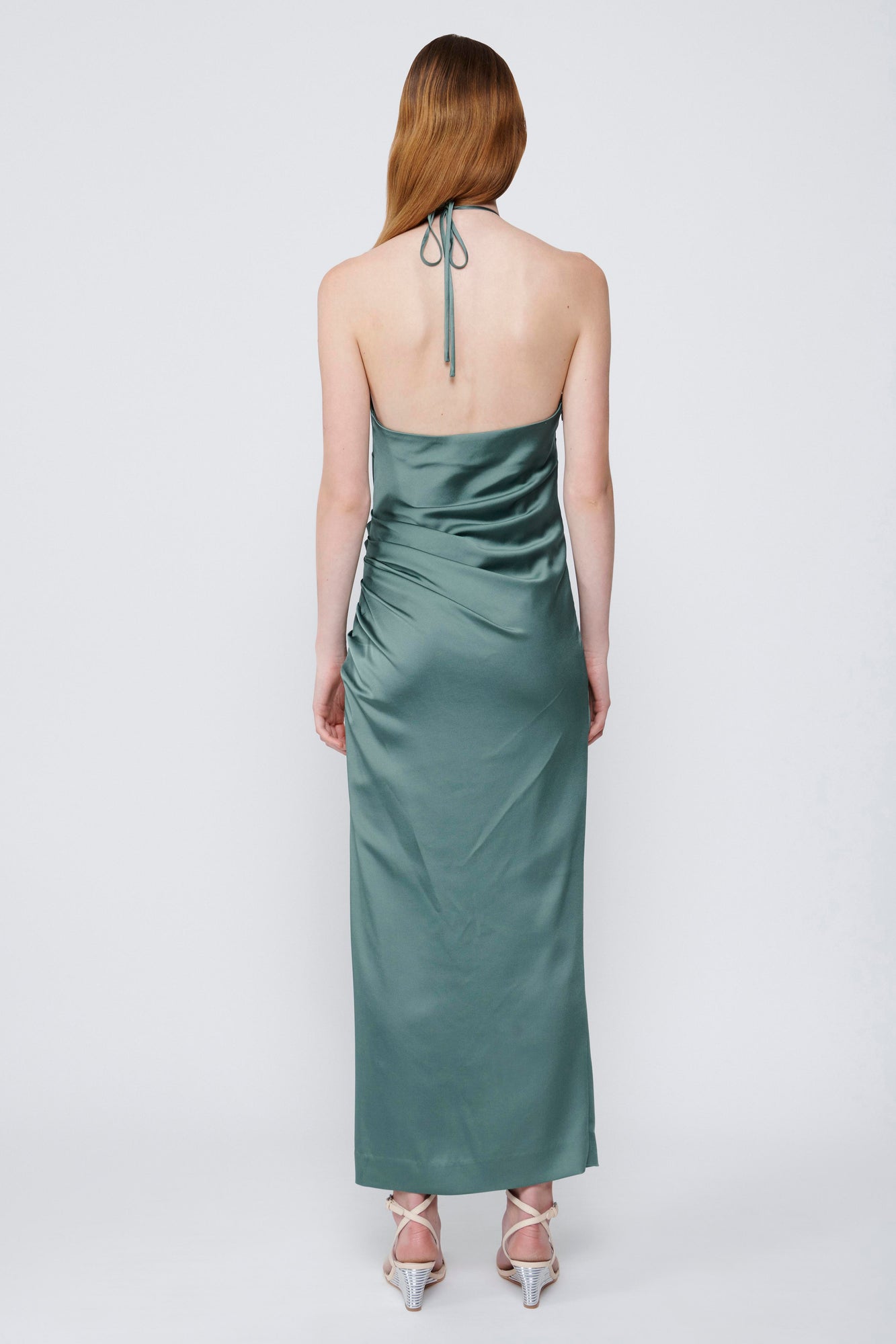 Sage green satin halter gown with draped bodice, open back, and ankle-length skirt.