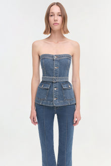 Woman wearing a strapless denim corset top with belt and matching jeans.