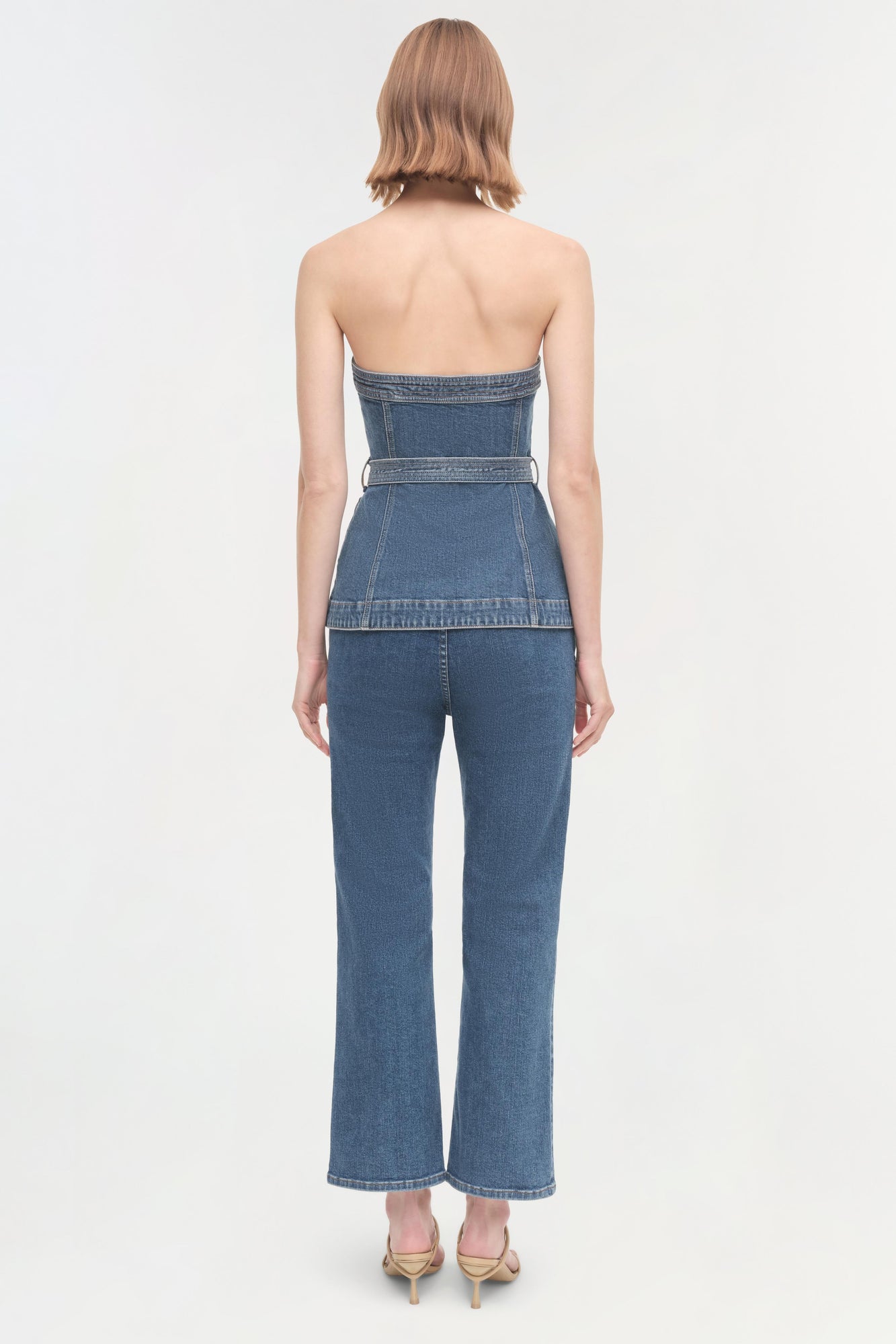 Woman wearing a blue denim halter top with matching high-waisted jeans, shown from behind.