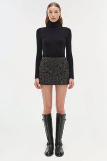 Black turtleneck sweater paired with gray embellished mini skirt and black knee-high boots.