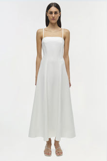 White cotton midi dress with thin straps and A-line skirt, shown on model with white sandals.