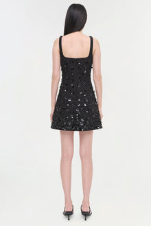 Black sequined sleeveless mini dress with square neckline, shown from back view on model wearing black heels.