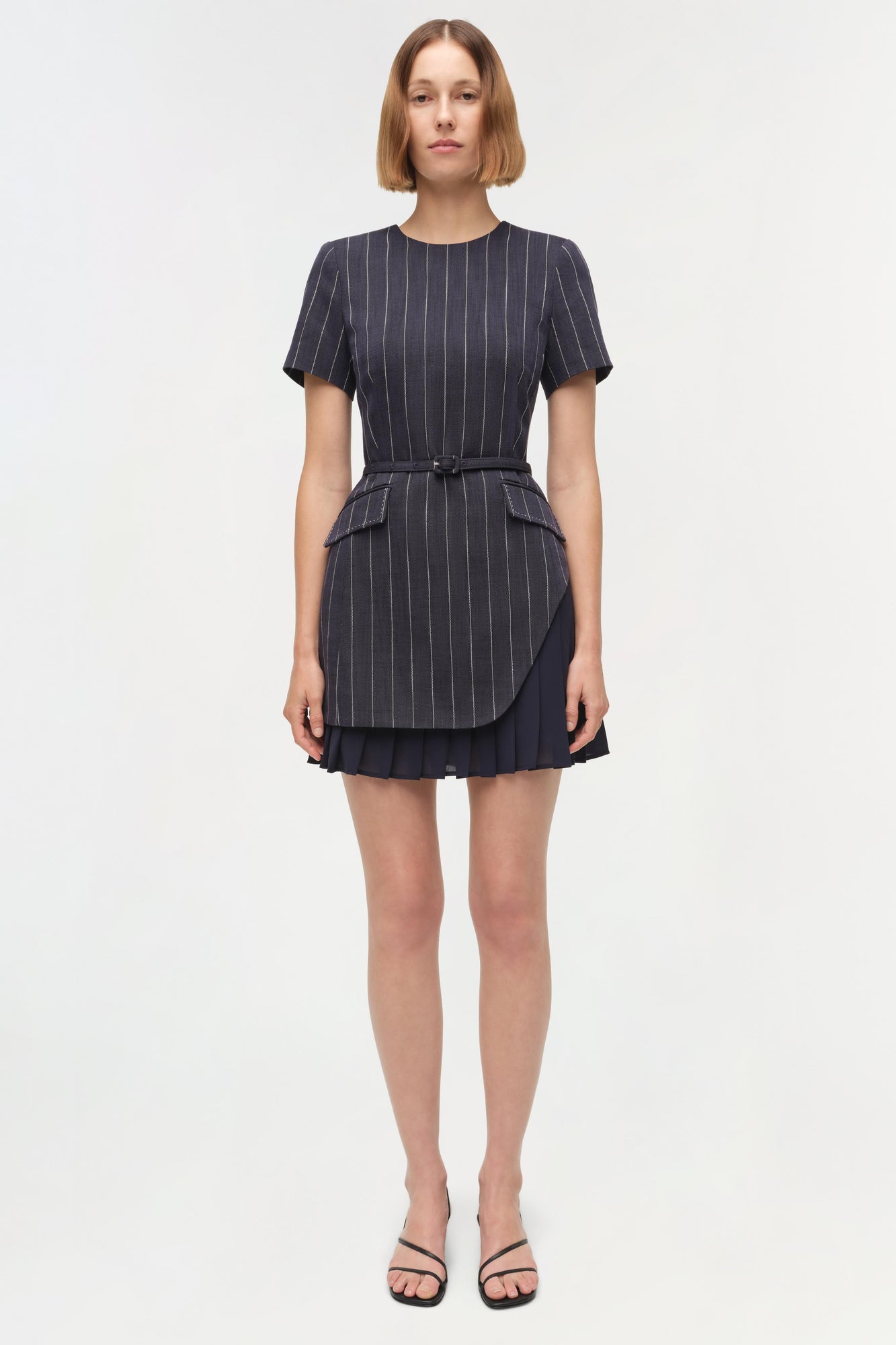 Navy pinstriped mini dress with short sleeves, cinched waist belt, peplum waist detail, and pleated skirt hem.