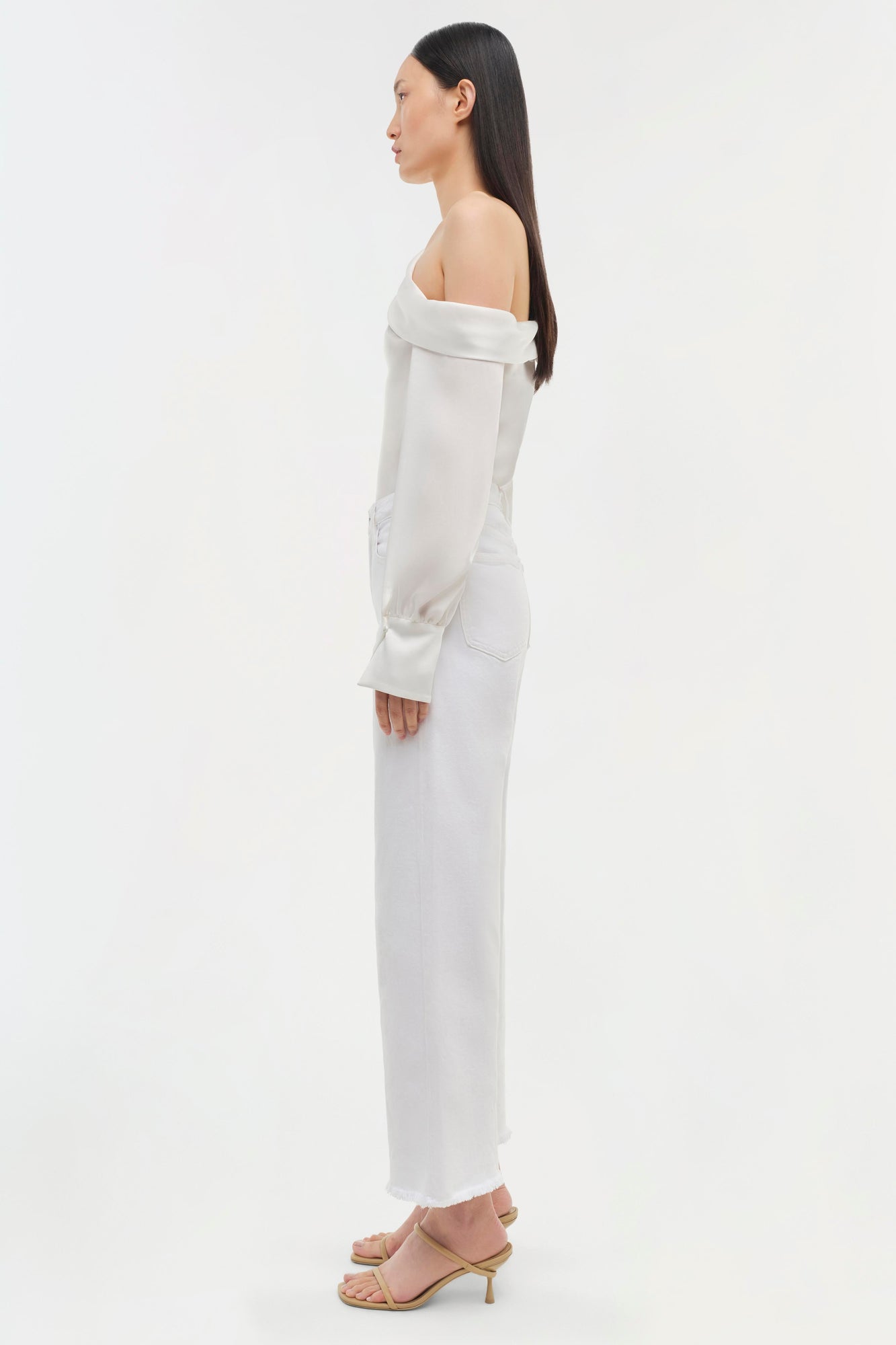 White off-shoulder top with long sleeves and matching high-waisted pants, shown from the side on a model.