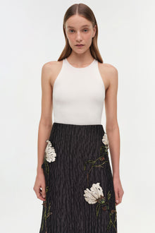 Black midi skirt with white floral jacquard pattern and textured fabric, paired with white ribbed tank top.