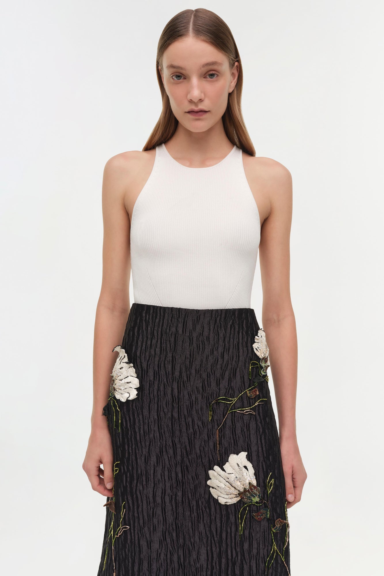 Black midi skirt with white floral jacquard pattern and textured fabric, paired with white ribbed tank top.