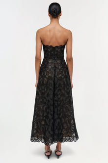 Black lace strapless midi dress with geometric patterning and scalloped hem, shown from back view.