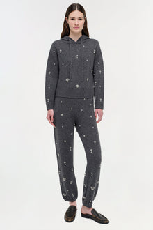 Woman wearing charcoal gray cashmere hoodie and joggers with scattered silver crystal embellishments throughout.