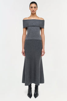 Woman wearing charcoal gray wool skirt with off-shoulder top and black boots against white background.