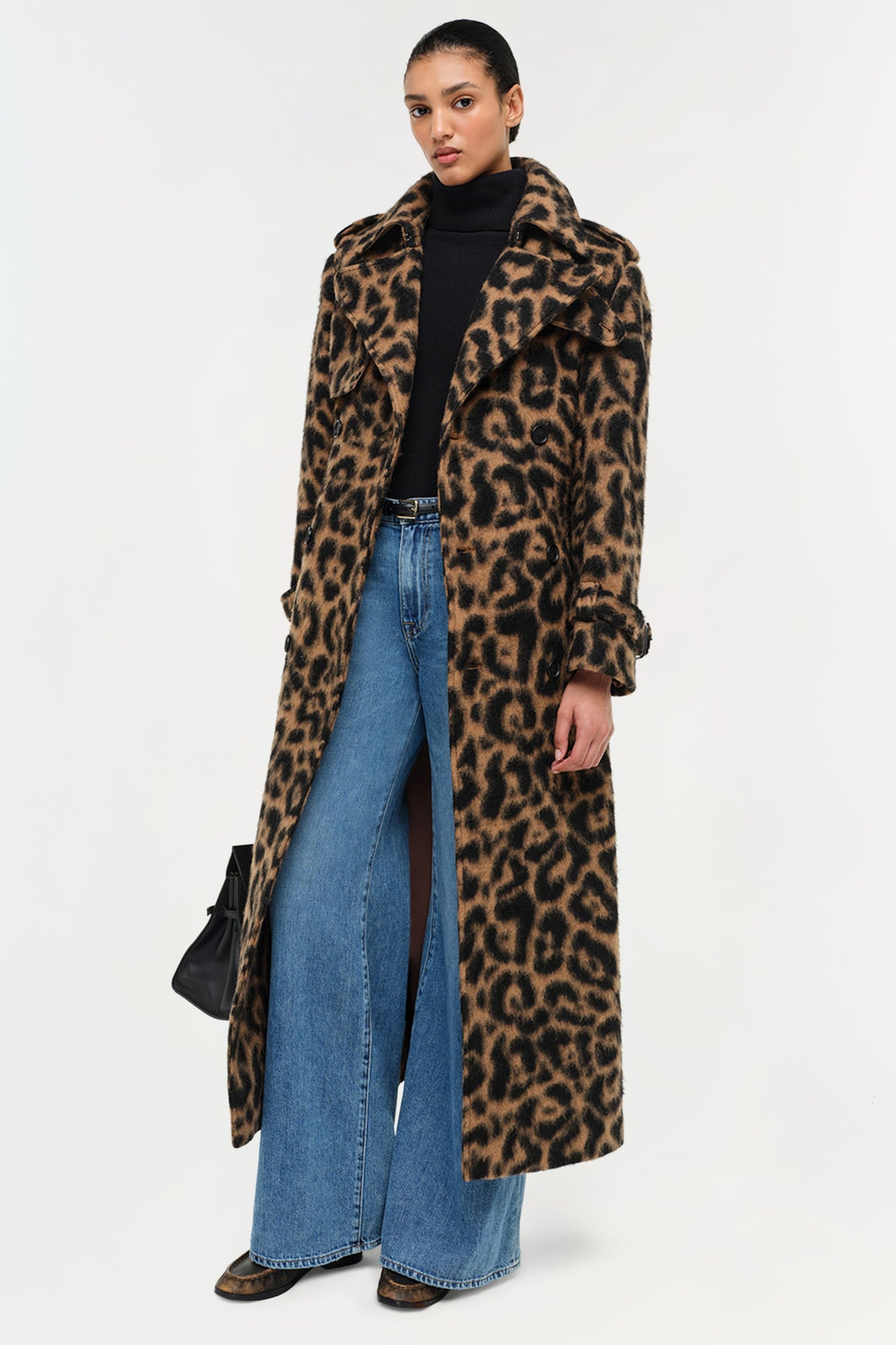 Leopard print wool overcoat with notch collar and long sleeves styled over black turtleneck and blue jeans.