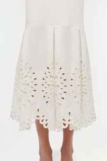 Cream knit midi skirt with ornate cutout embroidery detail along the hem, displayed on a model.