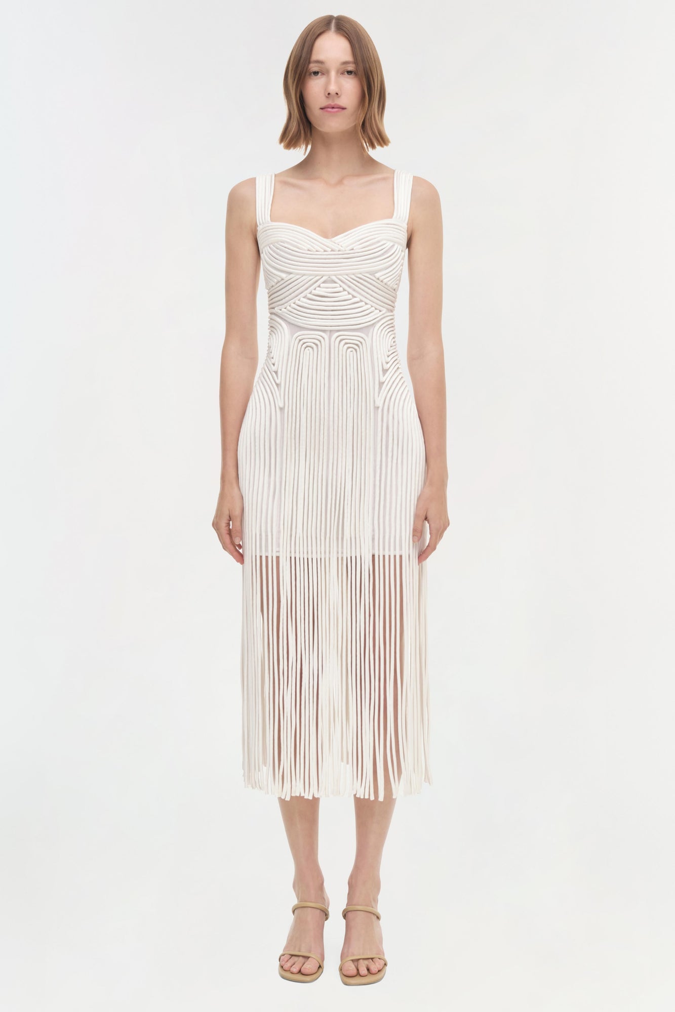 White sleeveless midi dress with geometric pleated pattern and fringe hem detail.