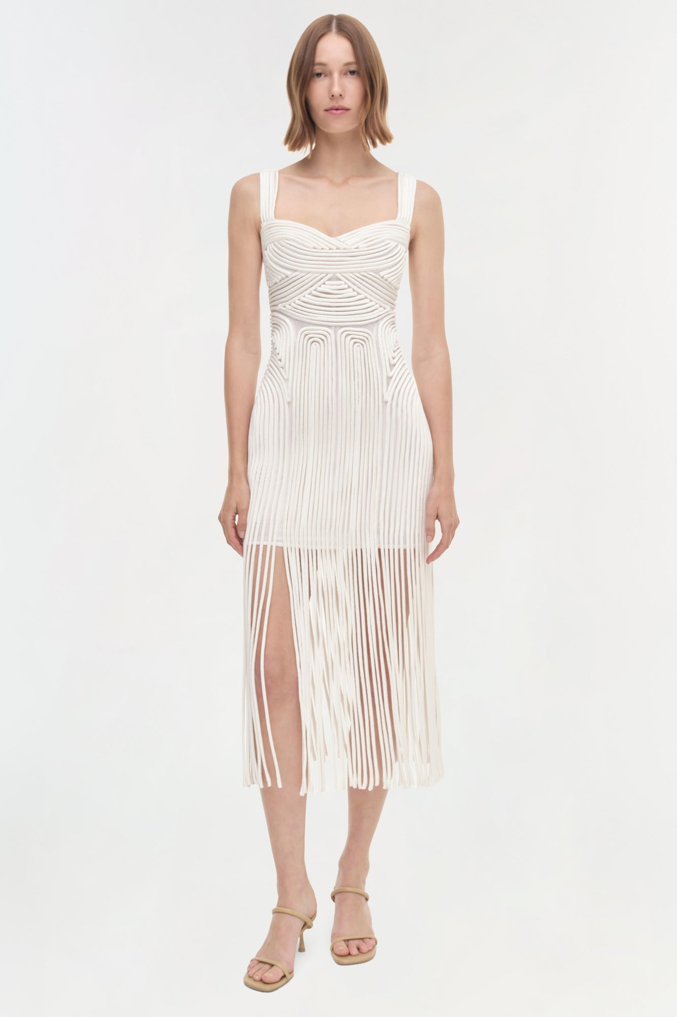 White sleeveless dress with pleated texture, sweetheart neckline, and high slit skirt.