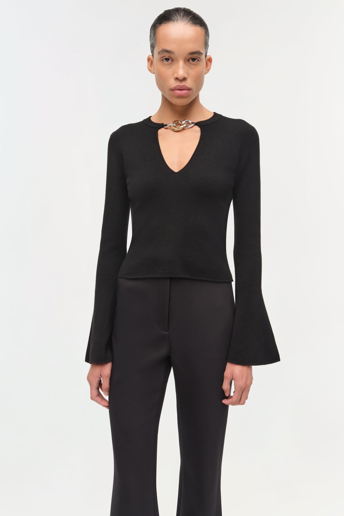 Black wool top with long flared sleeves and a choker neckline with chain detail.