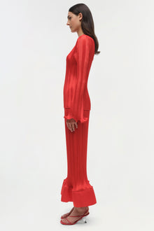Red ribbed long-sleeve top with flared hem, shown on model in side profile view.