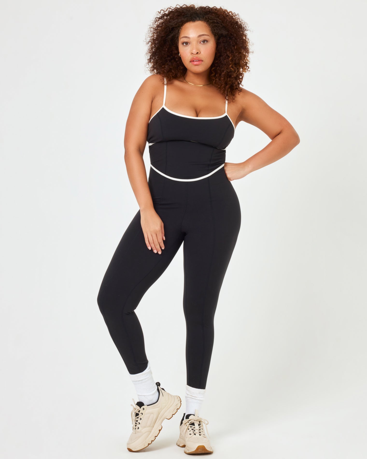 Front view of plus size model wearing the Ace Jumpsuit in black-cream with cream contrast piping.
