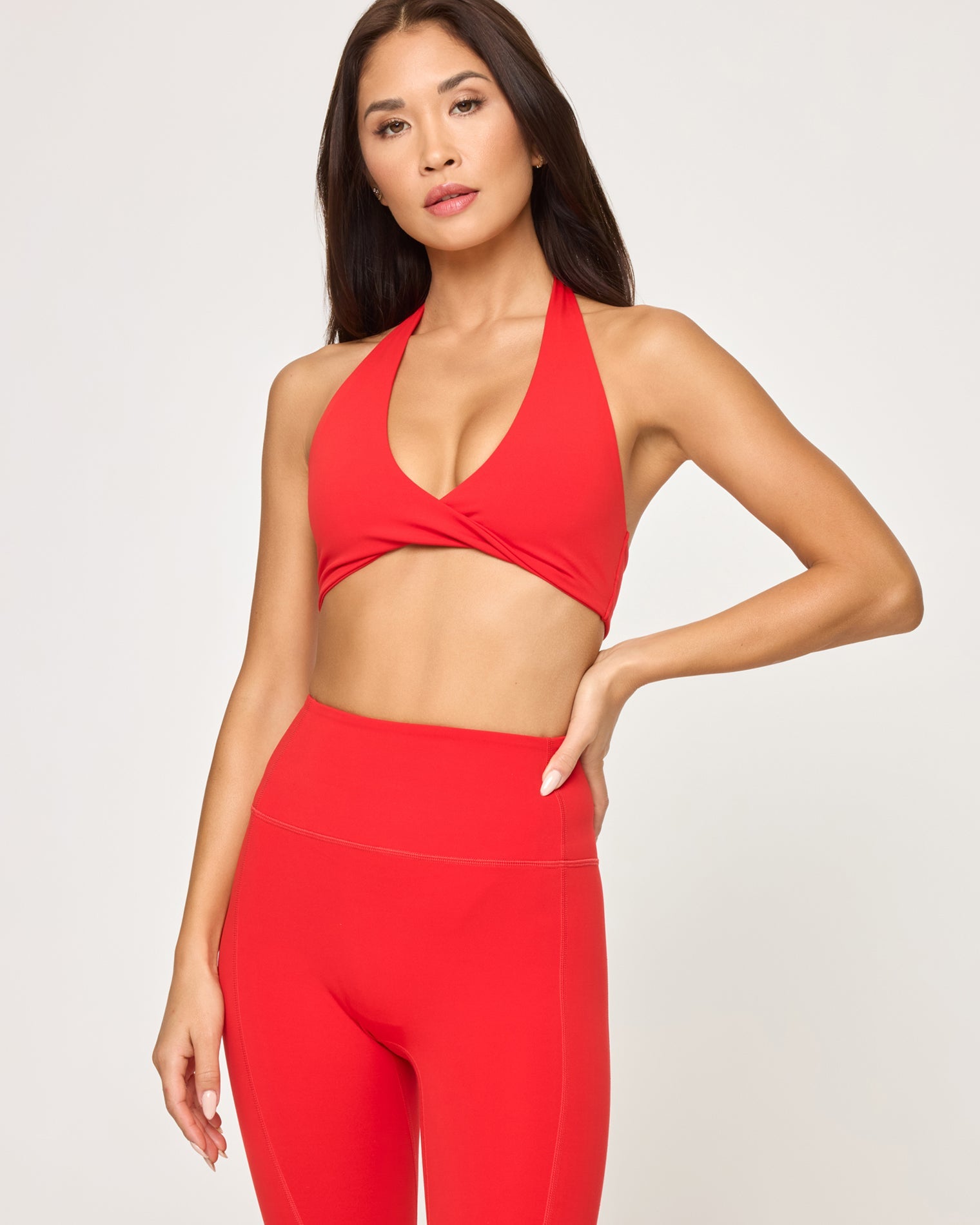 Close-up front studio view of model wearing the Jeanne Bra in flame with matching flame Level Up Legging, hand on hip.