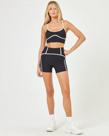 Front view of model wearing the Revel Top in black-cream with matching black-cream Revel Short and white sneakers.