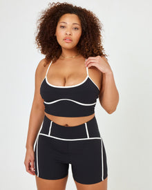 Close-up front view of model wearing the Revel Top in XL showing the scoop neckline and cream piping, with matching black-cream Revel Short.