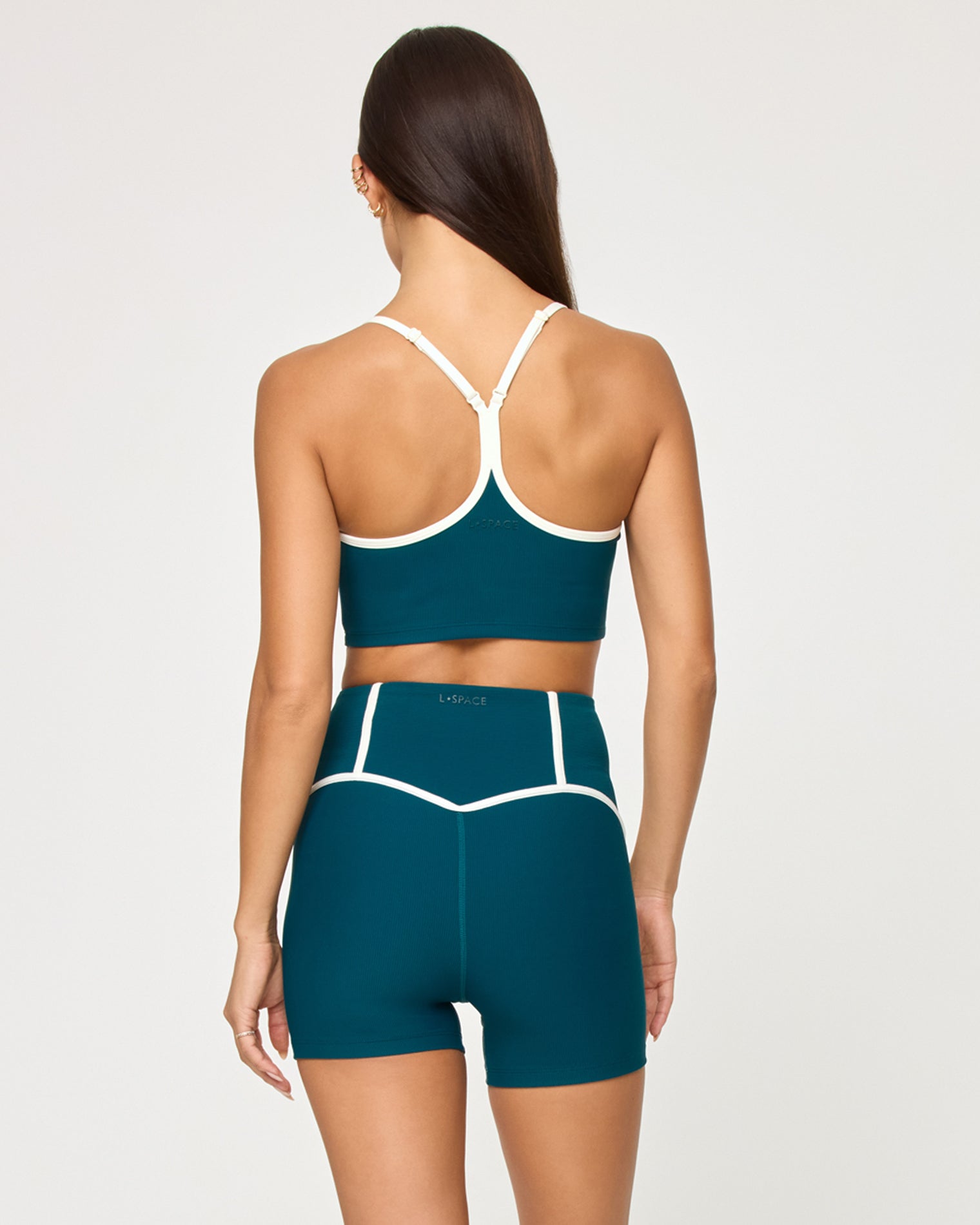 Back view of model wearing the Revel Top in deep teal-cream showing the crossback strap detail with cream piping, with matching deep teal-cream Revel Short.
