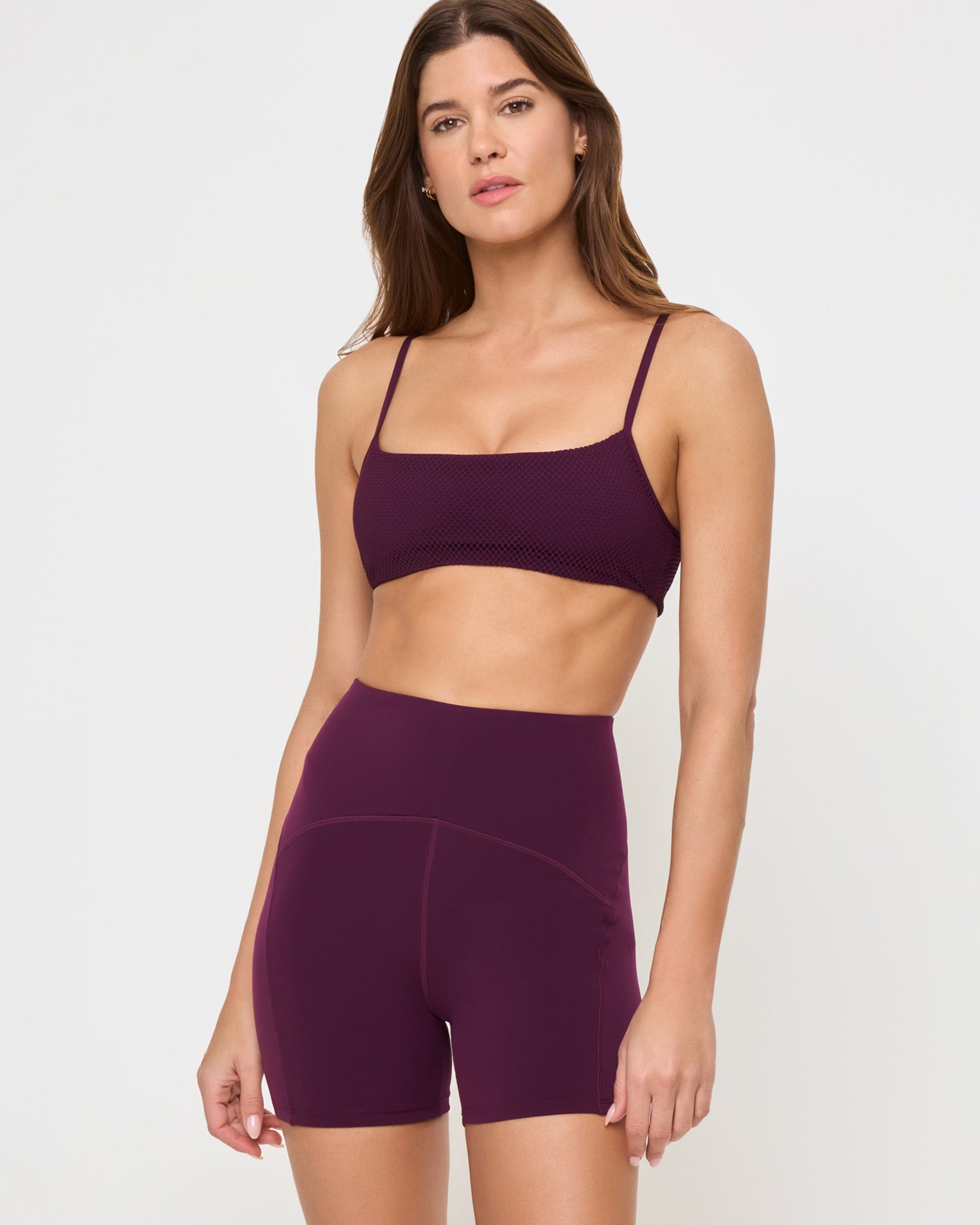 Close-up front view from the knees up of the LSPACE En Pointe Short in plum on a model against a white background, highlighting the waistband and silhouette of the high-waist active shorts.