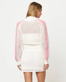 Back studio view of the Heart Stopper Sweater and Skirt in cream, a cream crochet-knit zip-front cropped sweater paired with a cream crochet mini skirt, pink stripe trim along the back, model looking over shoulder.