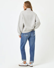 Back full-length studio view of the Crush Sweatshirt in Heather Gray, a heather gray oversized quarter-zip sweatshirt, styled with cuffed blue jeans and Adidas sneakers.