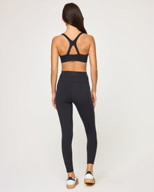 Back view of model wearing the Contender Legging in black with matching black sports bra.
