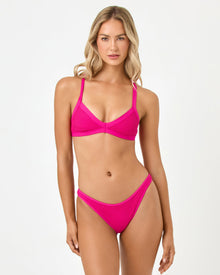 Woman wearing a bright pink bikini set on a white background