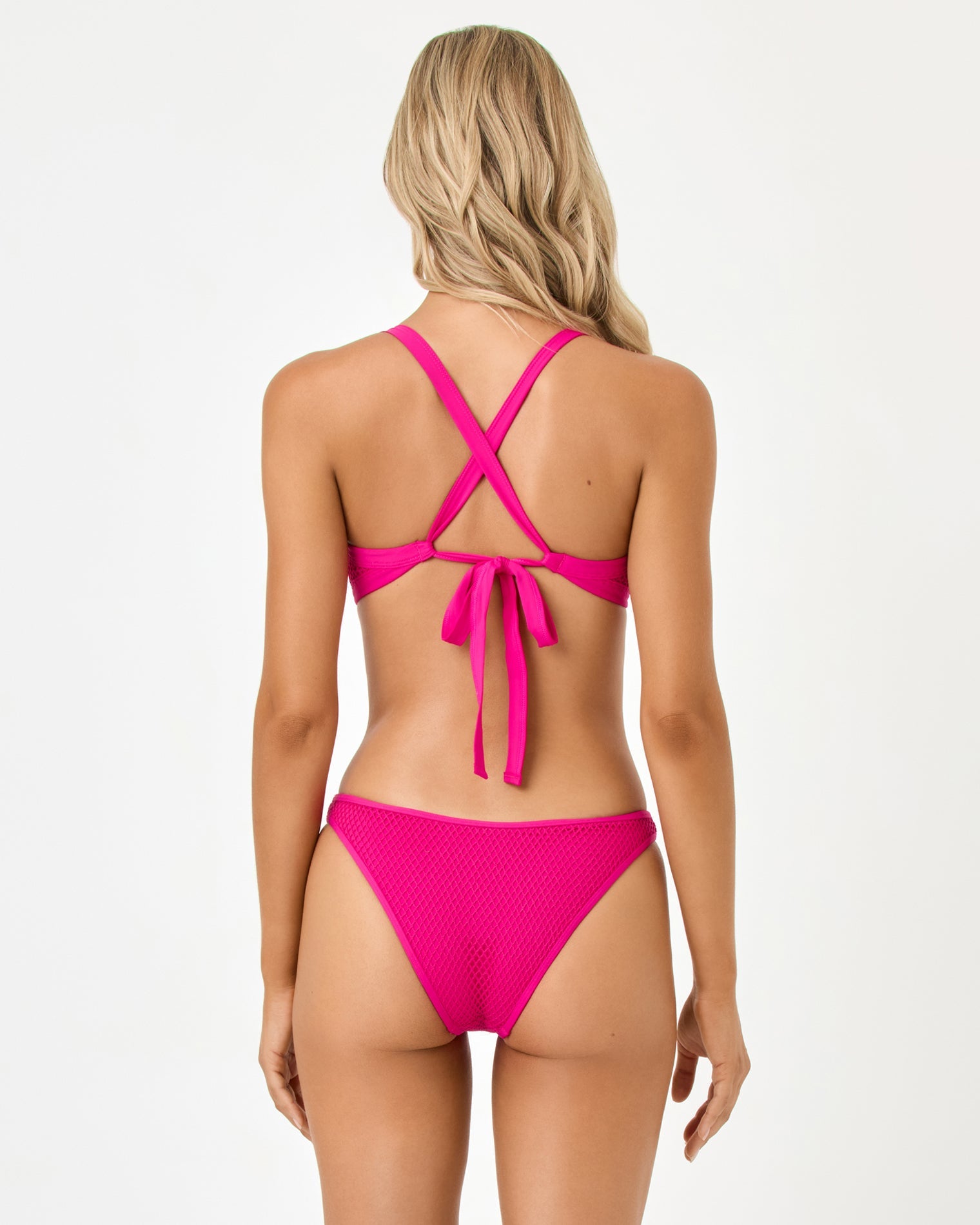 Back view of woman wearing a pink bikini with criss-cross straps on a white background
