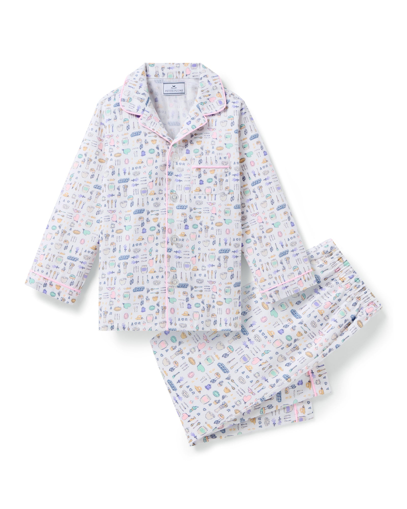 The Kid's Twill Pajama Set in Baking Spirits Bright features white long-sleeve button-up top and long pants with a colorful print of various small household and travel items.
