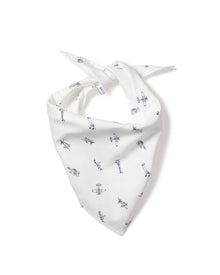 A fluffy white dog with small ears wears the Petite Plume Par Avion Dog Bandana featuring a blue floral pattern. The happy pup lies on a light wooden floor, looking up with its mouth open, showcasing the perfect blend of style and comfort in dog accessories.