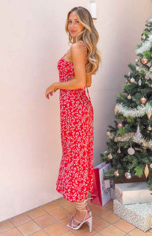 Full length front view of a red floral midi dress with a square neckline, thin straps, and a side slit