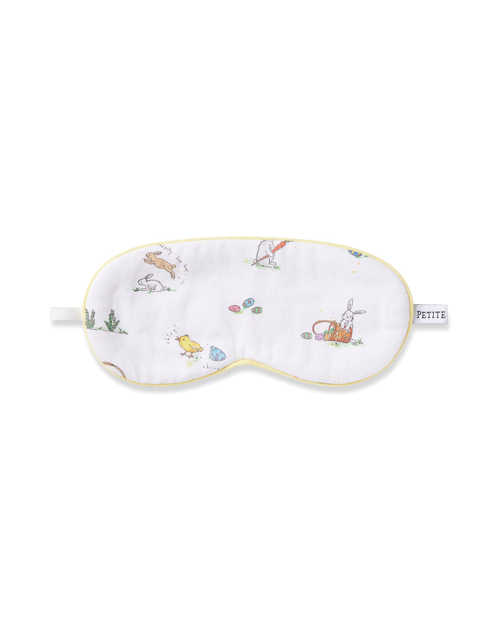 A young boy wears a Kid's Twill Sleep Mask in Easter Frolic, featuring colorful animal and nature prints, along with matching white pajamas. He smiles softly against a plain, light background.